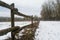 Snowy field behind wooden fence during february