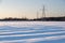 Snowy fields with forest and electricity towers in the background