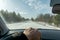 Snowy forest road during snowfall and strong wind. View of the road through the windshield of the car