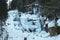 Snowy and frozen natural waterfall. Wild natural stream in winter. Slow shutter speed. Motion photography.