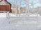 Snowy gate and red barn in the background a winter day