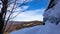 Snowy hilly landscape view with tree branch and a rock in the foreground, Jeseniky