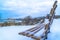Snowy hilly terrain by the frosted Utah Lake in winter with empty outdoor bench