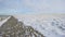 Snowy iced rocks of a dike along a white frozen lake in wetland under a blue cloudy sky in winter