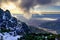 Snowy landscape on the rocky mountains of Madrid, dark clouds beginning to cover the sky and the sun setting on the horizon