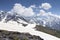 Snowy mountains. Mountain peaks covered by snow on sunny day with clouds. Caucasus nature. Rocks and stones in highlands