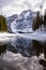 Snowy mountains reflected at the first thaw of the lake