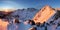 Snowy mountains under orange sunset sky