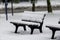 Snowy park bench with light snowfall