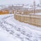 Snowy path with footprints along a wooden fence