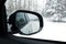 Snowy road and forest from the side mirror of the car. view from the passenger seat window