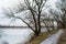 Snowy road near dark winter forest close to melting river