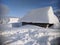 Snowy roof of a mountain cottage among the snowdrifts