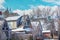 Snowy roofs in upscale neighborhood with spires and chimneys and gables under blue sky