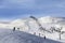 Snowy ski track prepared by snowcat, chair-lift, skiers and snowboarders in ski resort