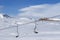 Snowy slope, chair-lift and blue sky with clouds at sun winter d