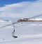 Snowy slope, chair-lift and blue sky with clouds at sun winter day