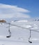 Snowy slope, chair-lift and blue sky with clouds at sunny winter day