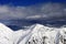 Snowy sunlit mountains and cloudy sky