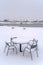 Snowy table and chairs with view of lake and homes