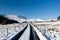 A snowy track leads towards snow capped mountains