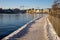 Snowy walking path at Stockholm bay on sunny freezing winter day with steaming water