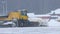 Snowy winter - a big snowplow removes snow from the path on the way