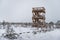 Snowy winter day at swamp. Small swamp trees and watchtower