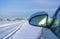 Snowy winter forest road background with car rearview mirror