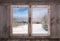 Snowy winter landscape. View out of an old rustic wooden window.