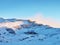 Snowy winter mountain and old stony cottage in small valley bellow peak. Clear blue sky.