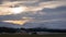 Snowy winter mountains with cloudy skies and farm land in the foreground