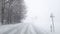 Snowy winter road among frozen forest after sleet. Cold weather, snowstorm, bad visibility