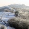 A snowy winters day on the Malvern Hills, looking over the ridge with a group of people on top of one of the hills in the backgrou