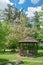 Snug cozy gazebo under blossoming trees on sunny summer day