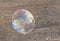 Soap bubble large iridescent with an iridescent pattern close-up against a background of stone