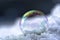 Soap bubble with rainbow reflections in the snow, winter still l