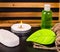 Soap, candle, bottle of oil, pumice and burlap on black table.