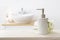 Soap dispenser and flowers on table in defocused bathroom background