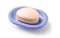 Soap on a soap dish isolated on a white background. Oval shaped beige soap bar in a violet blue plastic soapbox for bathroom and