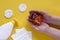 Soap in womanâ€™s hands, plastic dispenser of liquid soap, cotton pads and paper wipes on yellow background. Top view.