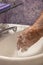 Soaping hands with running water bathroom sink vertical