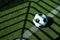 Soccer ball black and white on artificial ground ground with shadows stripes, on the line