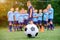 Soccer ball and blurred kids soccer team with coach on the field