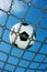 Soccer ball in chain net white and black football, blue sky