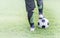 Soccer ball with child feet player on green grass