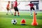 Soccer ball and cone marker on green artificial turf with blurry of soccer player training