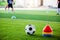 Soccer ball and cone marker on green artificial turf with blurry of soccer player training