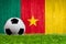 Soccer ball on grass with Cameroon flag background