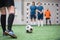 Soccer ball on green footaball field with legs of sportswoman going to kick it